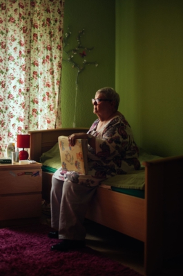 Frau hält Fotobuch und sitzt auf dem Bett für LFB Wegbegleiter Projekt Maximilian Gödecke Photography Berlin