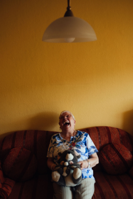 Helga sitzt lachend auf der Couch für LFB Wegbegleiter Projekt Maximilian Gödecke Photography Berlin