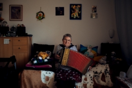 Waltraud sitzt mit Akkordeon auf der Couch Maximilian Gödecke Photography Berlin